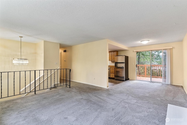 unfurnished living room with a textured ceiling, a chandelier, and carpet