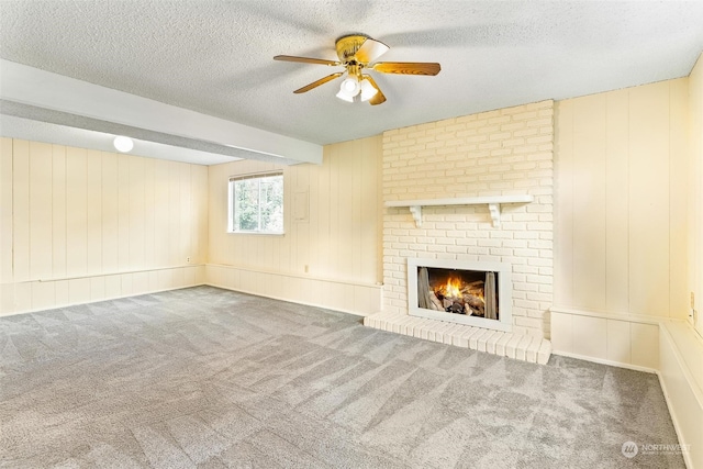 unfurnished living room with ceiling fan, carpet floors, a fireplace, and a textured ceiling