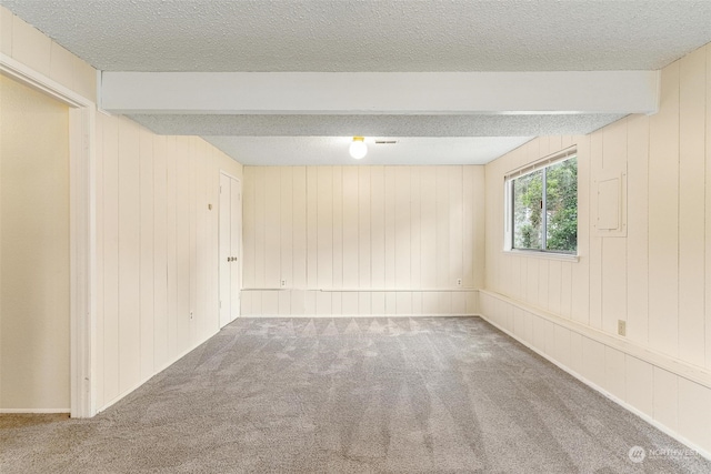 empty room with a textured ceiling, carpet floors, and beam ceiling