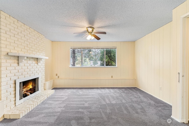 unfurnished living room featuring a fireplace, a textured ceiling, ceiling fan, and carpet floors