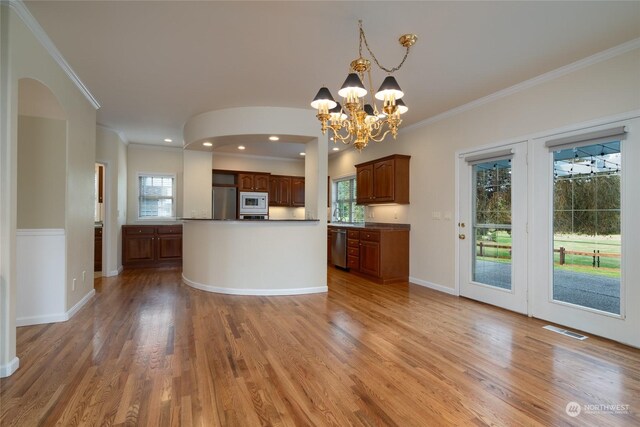 kitchen with stainless steel appliances, ornamental molding, hardwood / wood-style flooring, hanging light fixtures, and a notable chandelier