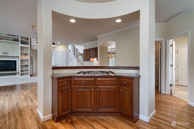 kitchen with stainless steel gas stovetop, light wood-style floors, arched walkways, and ornamental molding