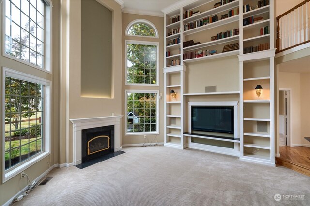 unfurnished living room with ornamental molding and light colored carpet