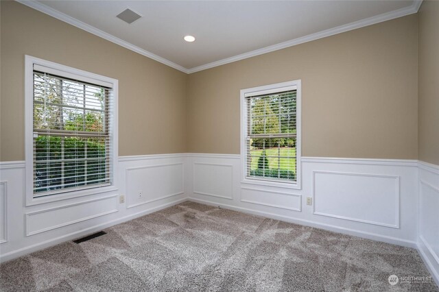 carpeted spare room with visible vents, a healthy amount of sunlight, crown molding, and a wainscoted wall