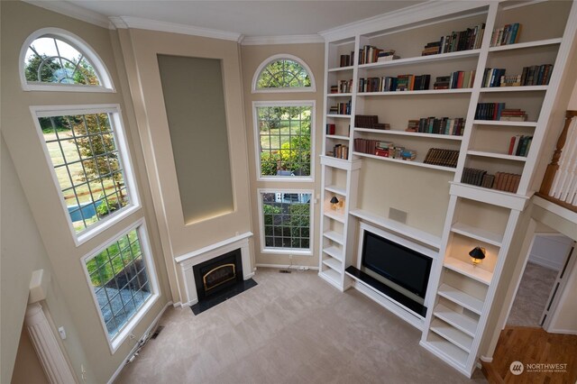 living room with a wealth of natural light, a fireplace with flush hearth, carpet floors, and ornamental molding