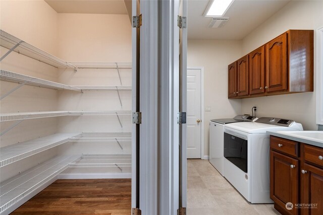 laundry area featuring visible vents, cabinet space, and washing machine and clothes dryer