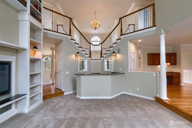 kitchen featuring ornamental molding, light colored carpet, an inviting chandelier, and a towering ceiling