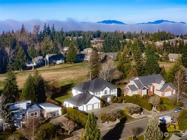 birds eye view of property featuring a view of trees, a mountain view, and a residential view