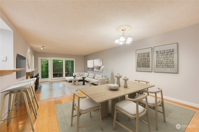 dining room featuring a notable chandelier, light hardwood / wood-style floors, and a textured ceiling