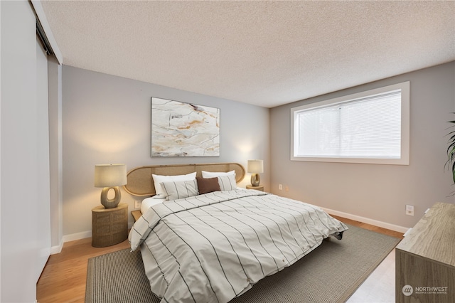 bedroom featuring light wood-type flooring, a closet, and a textured ceiling