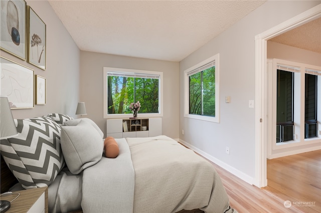 bedroom with light wood-type flooring and a textured ceiling