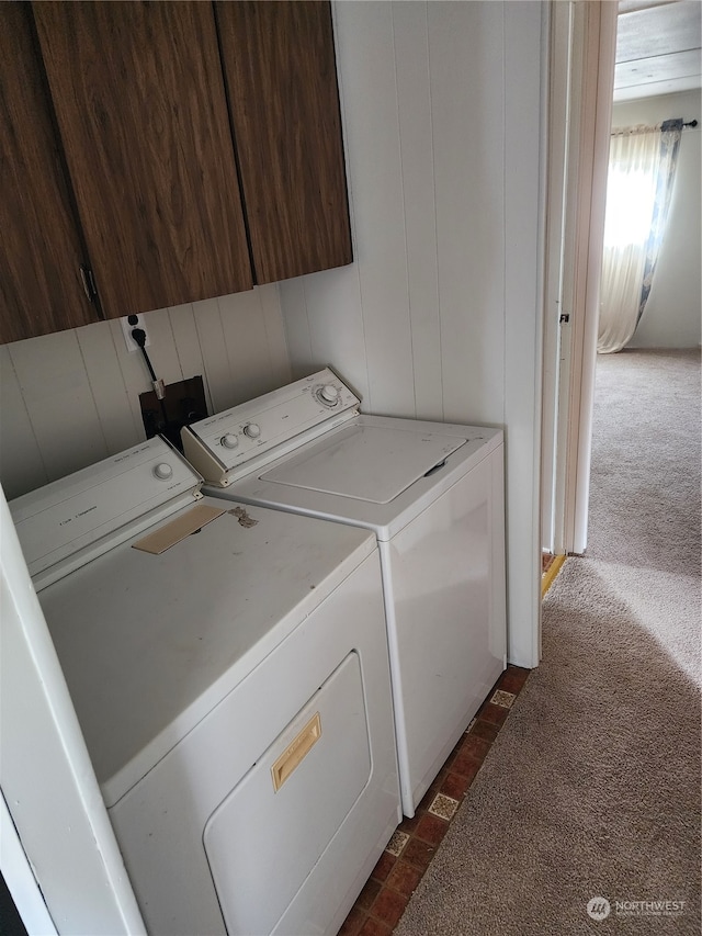 clothes washing area featuring dark carpet, washer and clothes dryer, and wood walls