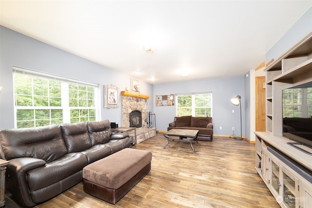 living room with light wood-type flooring and a stone fireplace