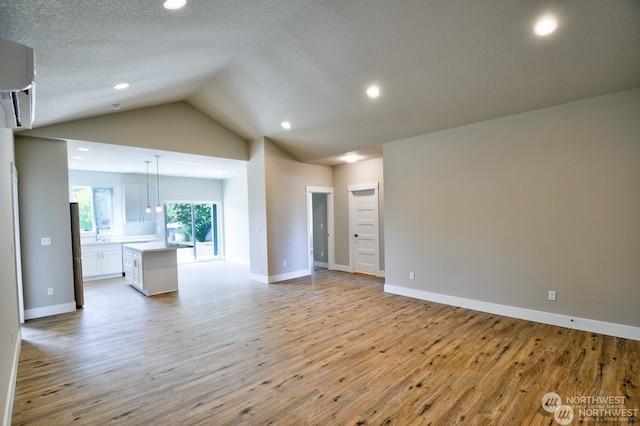 unfurnished living room featuring a textured ceiling, light hardwood / wood-style flooring, and vaulted ceiling