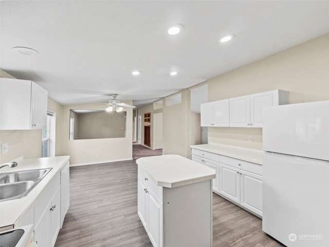 kitchen with white refrigerator, light hardwood / wood-style floors, white cabinetry, a kitchen island, and ceiling fan