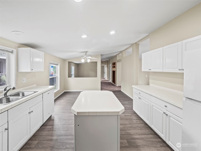 kitchen with ceiling fan, white cabinets, sink, a kitchen island, and dark hardwood / wood-style flooring