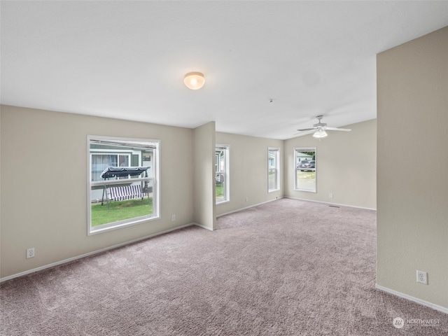 carpeted empty room with ceiling fan and a wealth of natural light