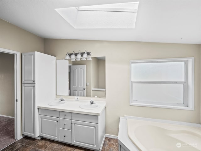 bathroom featuring vaulted ceiling with skylight, a bath, and vanity