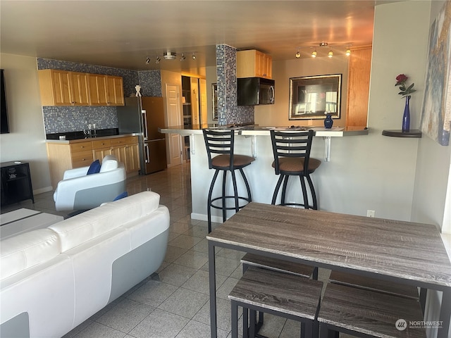 kitchen featuring high quality fridge, backsplash, a breakfast bar, and rail lighting