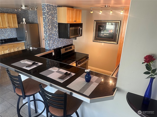 kitchen with appliances with stainless steel finishes, backsplash, tile counters, and a kitchen breakfast bar