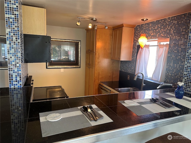 kitchen with sink, kitchen peninsula, backsplash, light brown cabinets, and decorative light fixtures