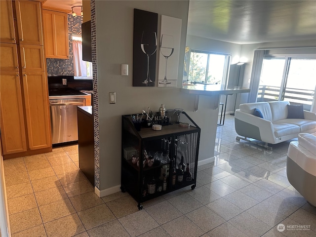 interior space featuring a kitchen breakfast bar, decorative backsplash, and stainless steel dishwasher