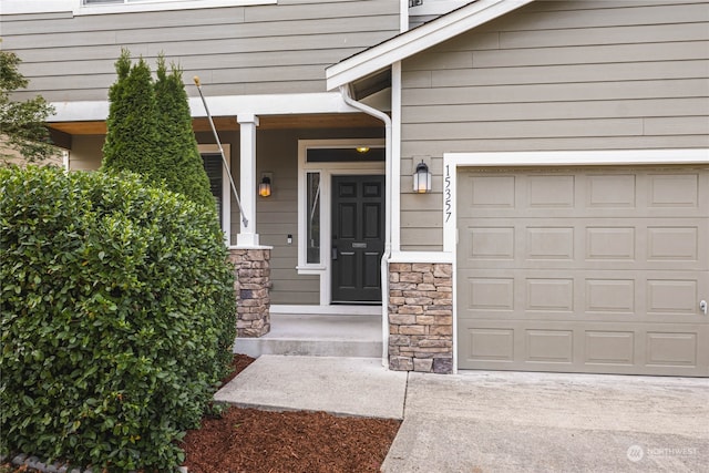 view of exterior entry with a garage and a porch