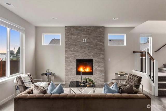 living room featuring stairway, wood finished floors, visible vents, baseboards, and a fireplace