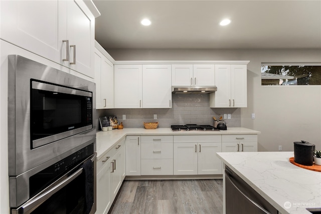 kitchen featuring white cabinetry, light stone counters, stainless steel appliances, and light hardwood / wood-style floors