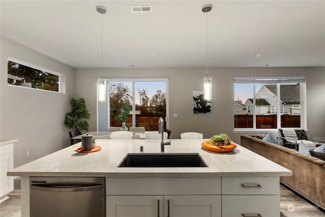 kitchen with an island with sink, decorative light fixtures, and sink