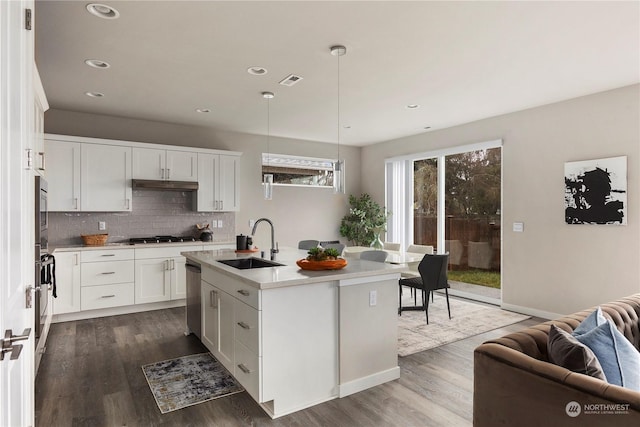 kitchen with stainless steel appliances, dark wood-style floors, a sink, backsplash, and light countertops