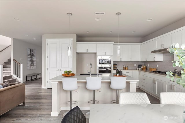 kitchen with under cabinet range hood, decorative backsplash, appliances with stainless steel finishes, and light countertops