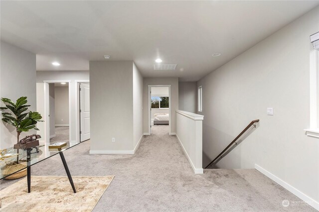 hallway featuring recessed lighting, baseboards, light colored carpet, and an upstairs landing