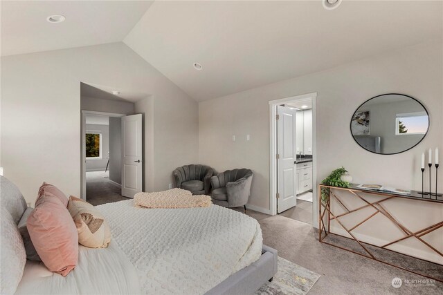 carpeted bedroom with vaulted ceiling, ensuite bathroom, and baseboards