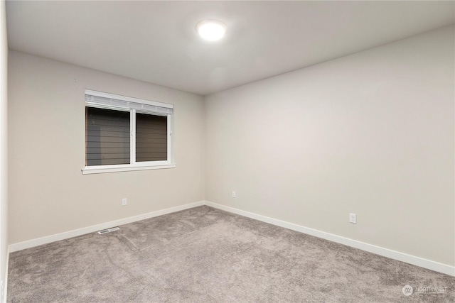 carpeted spare room featuring visible vents and baseboards