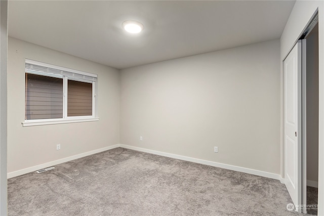 unfurnished bedroom with light colored carpet and a closet