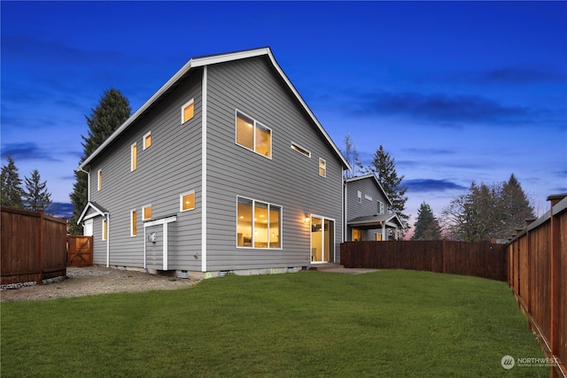 back house at dusk featuring a yard