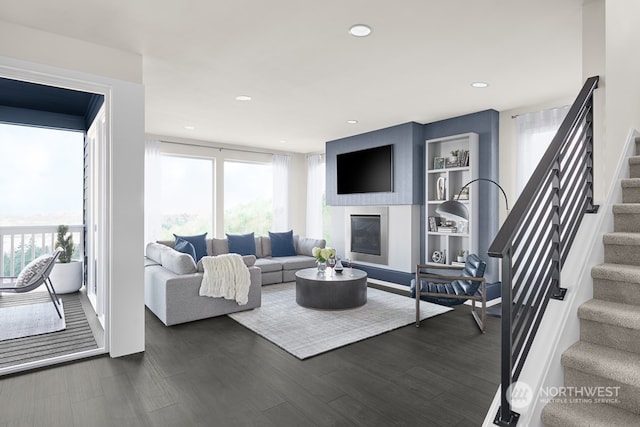 living room with dark hardwood / wood-style flooring, a wealth of natural light, and a large fireplace