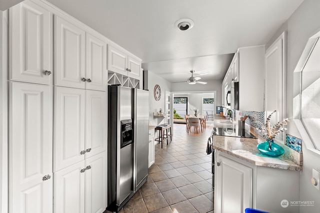 kitchen featuring ceiling fan, stainless steel appliances, white cabinetry, and tile patterned floors