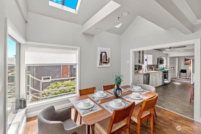 dining area with sink, ceiling fan, dark hardwood / wood-style flooring, and lofted ceiling with skylight