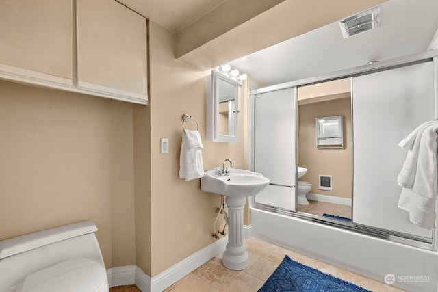 bathroom with combined bath / shower with glass door, toilet, and tile patterned flooring