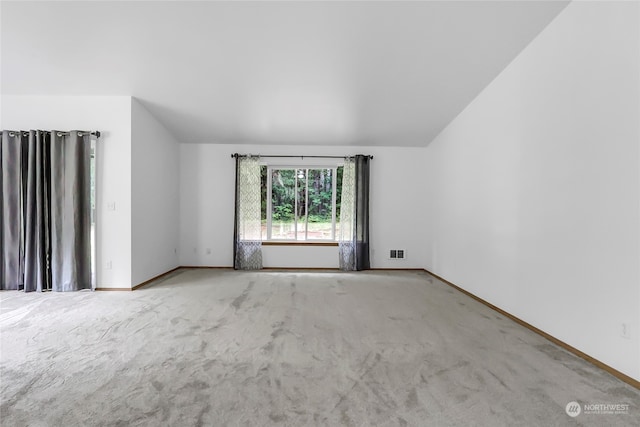 carpeted empty room with vaulted ceiling