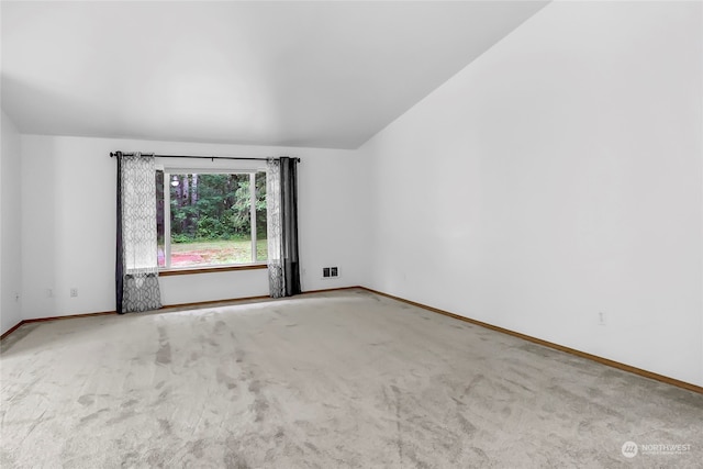 carpeted empty room featuring vaulted ceiling