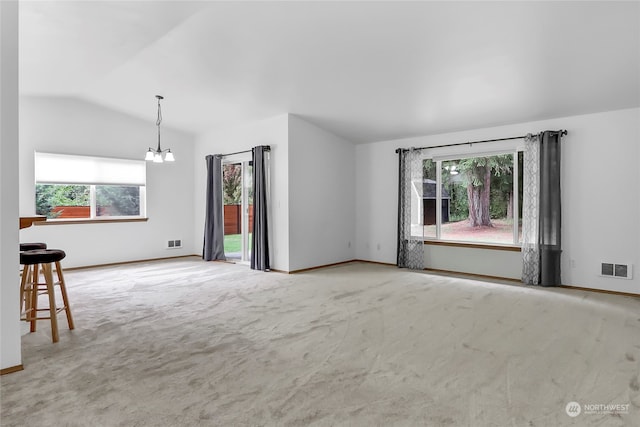 interior space with lofted ceiling, a healthy amount of sunlight, an inviting chandelier, and carpet