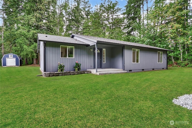 rear view of property with a storage unit, a lawn, and a patio area