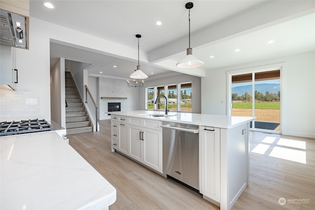 kitchen featuring decorative light fixtures, appliances with stainless steel finishes, light hardwood / wood-style floors, sink, and white cabinets