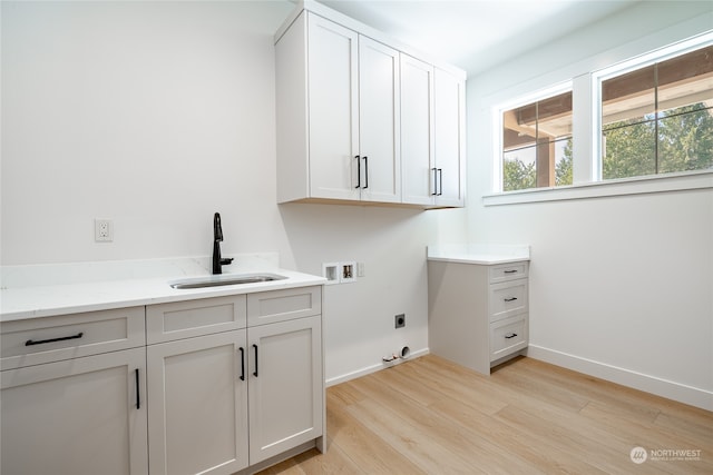 laundry room with cabinets, hookup for a washing machine, sink, hookup for an electric dryer, and light hardwood / wood-style floors