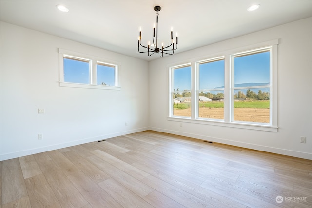 spare room with a water view, a notable chandelier, and light hardwood / wood-style floors