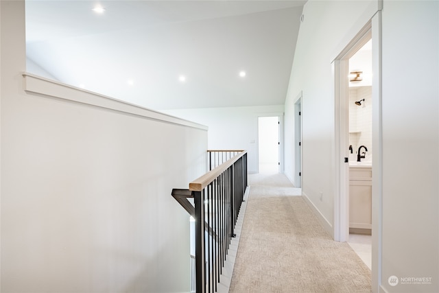 hall featuring light colored carpet and vaulted ceiling