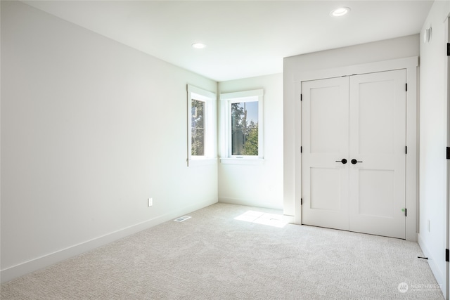 unfurnished bedroom featuring a closet and light carpet